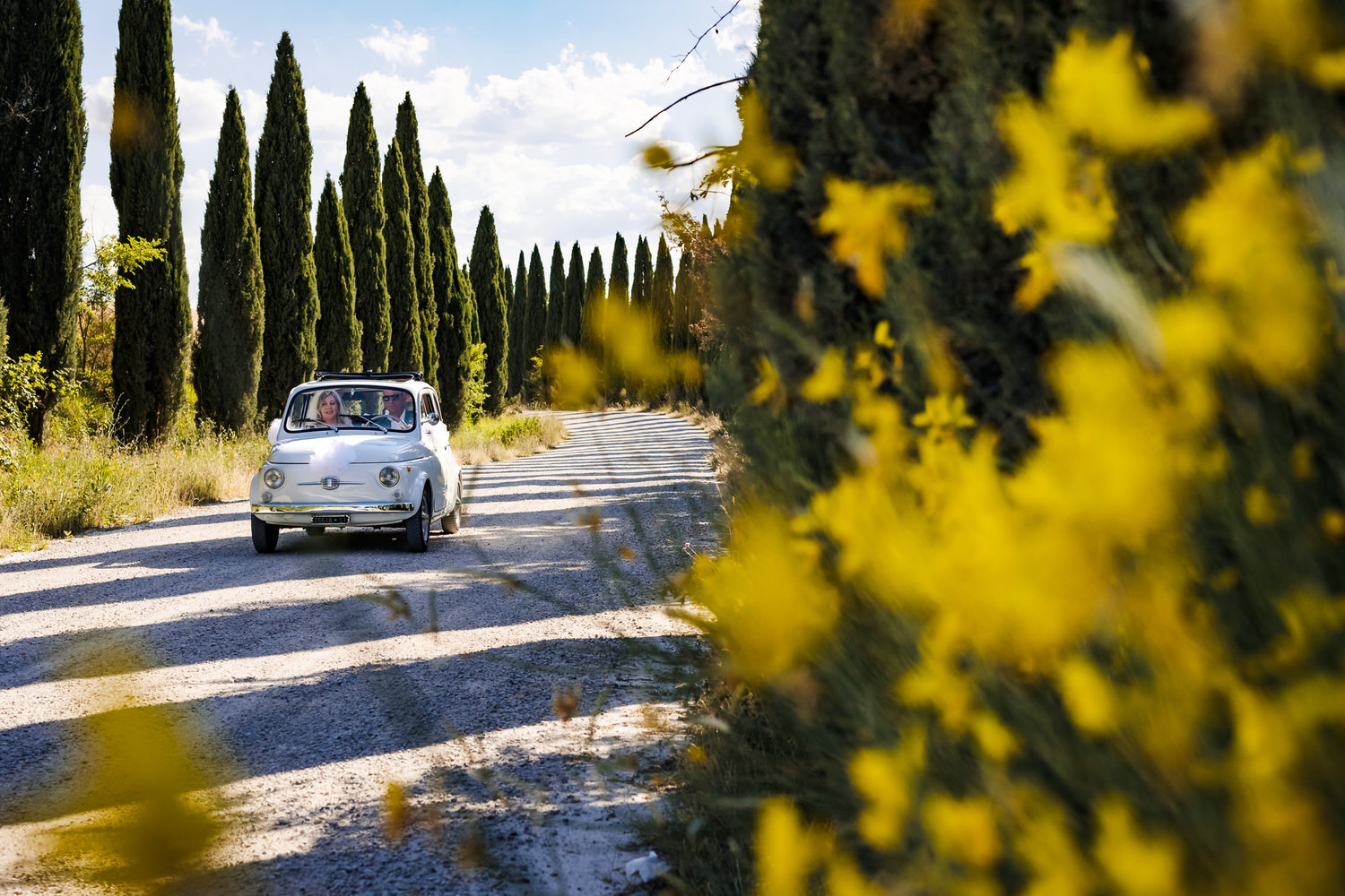 fiat met bruid en bruidegom tussen de cipressen tijdens een bruiloft in italie