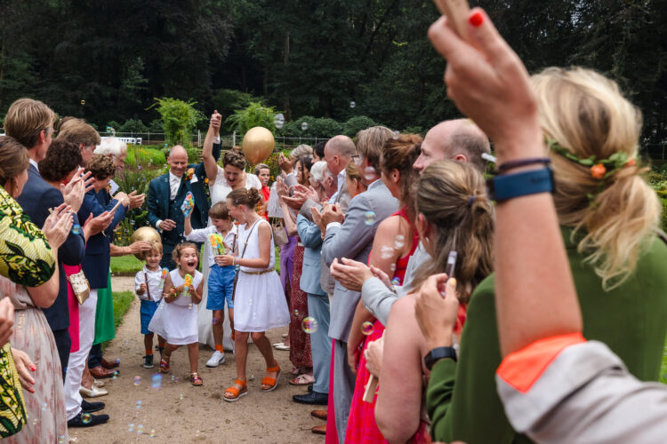 bruidspaar loopt met bruidskinderen tussen gasten door tijdens bruiloft op Groot Warnsborn in Arnhem