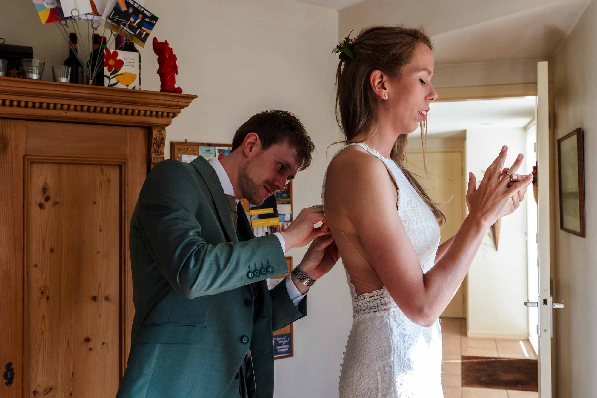 trouwjurk van bruid wordt dichtgeknoopt