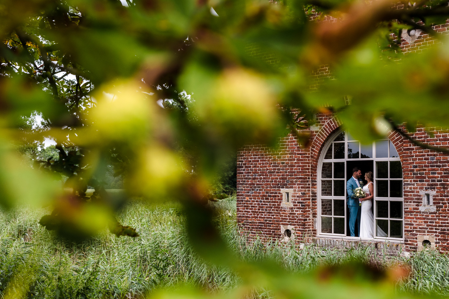 bruidspaar voor het raam van kasteel tongelaar