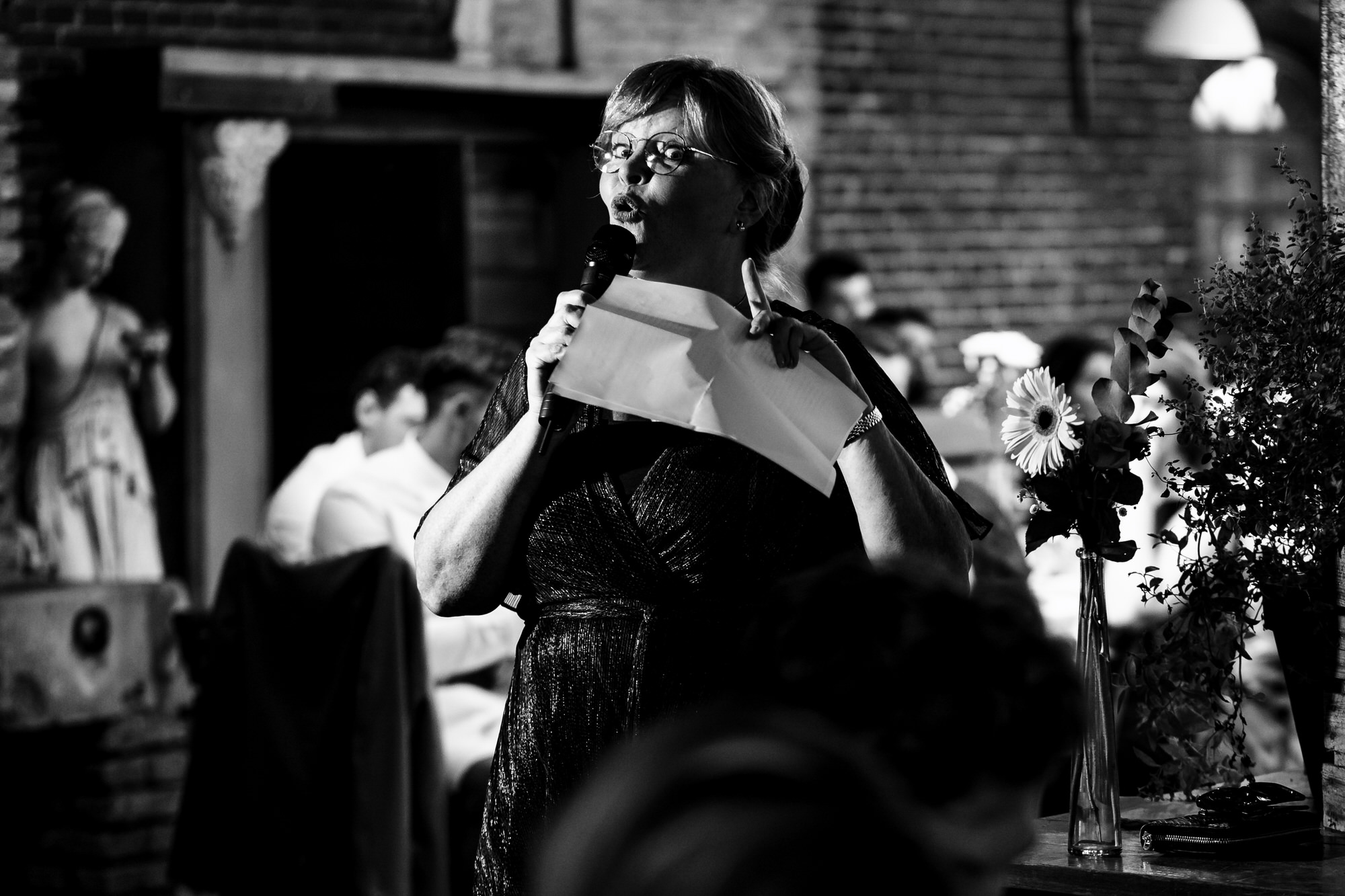 moeder spreekt bruidspaar toe tijdens diner op bruiloft