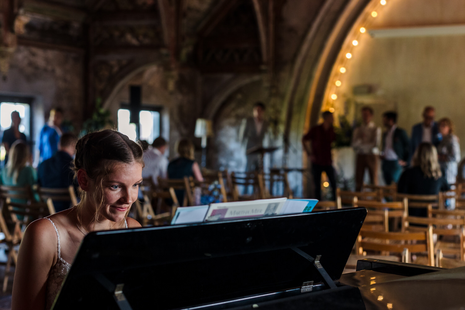 bruid speelt piano terwijl gasten de metaal kathedraal in lopen voor de start van een bruiloft