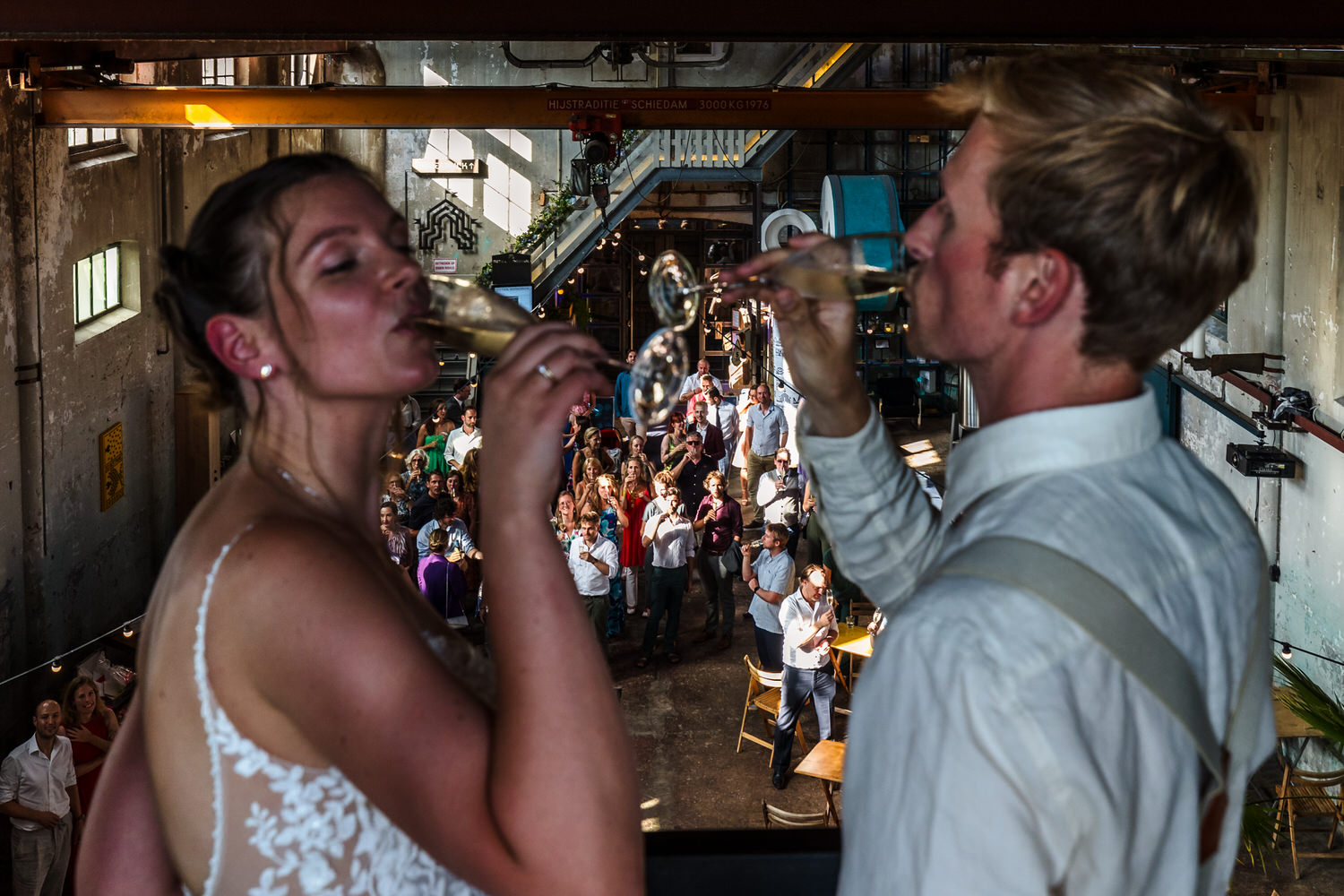 bruidspaar drinkt champagne met gasten in ontvangsthal metaal kathedraal