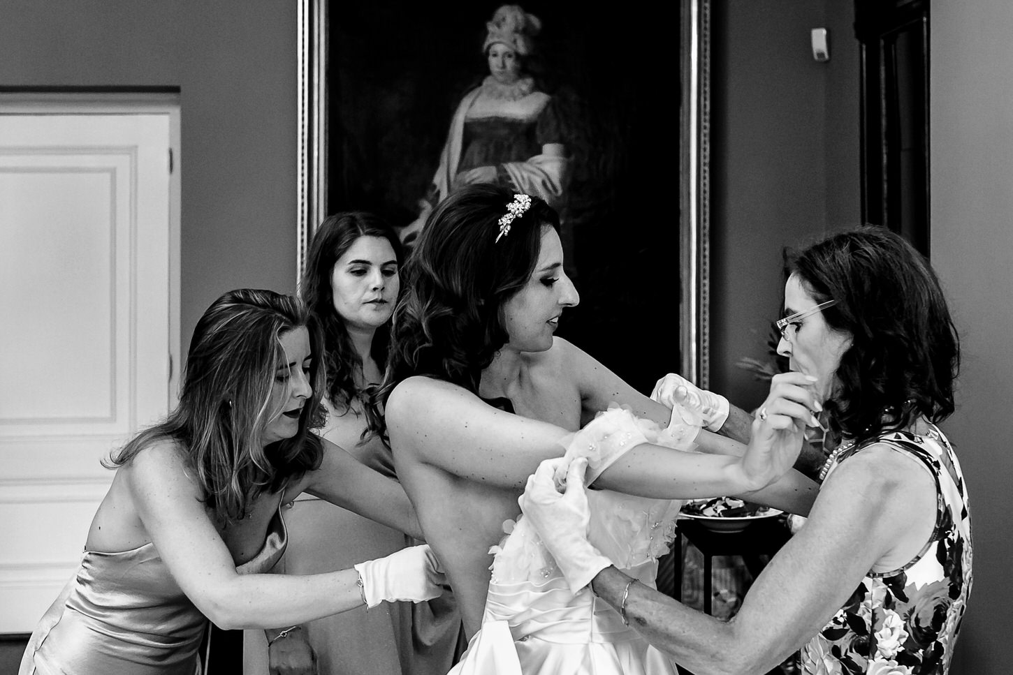 moeder en bruidsmeisjes help bruid in trouwjurk