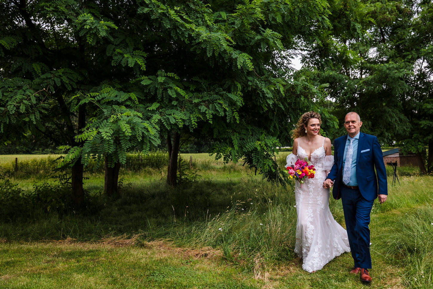 bruid loopt met vader naar de ceremonie tijdens een bruiloft in noord-limburg
