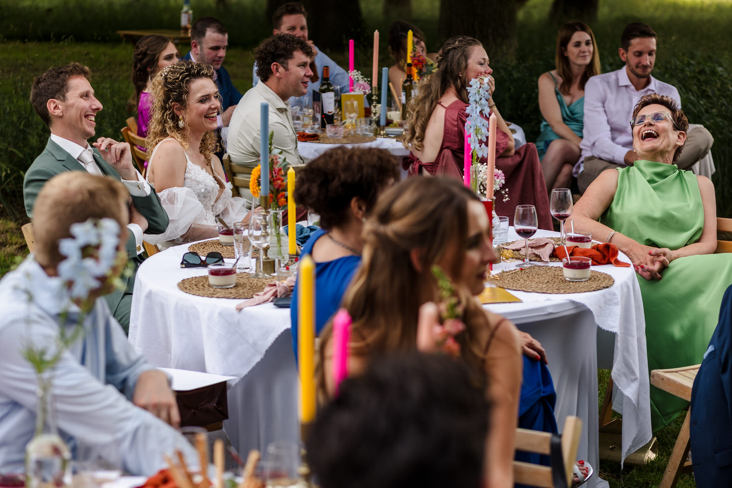 lachende gasten tijdens een bruiloftsdiner in de openlucht