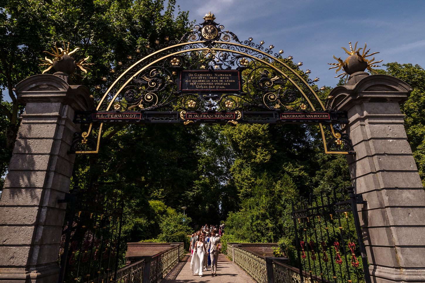 bruidspaar en gasten verlaten het valkhofpark