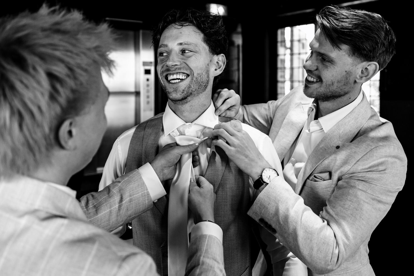 twee vrienden helpen bruidegom met aantrekken pak tijdens getting ready in nijmegen
