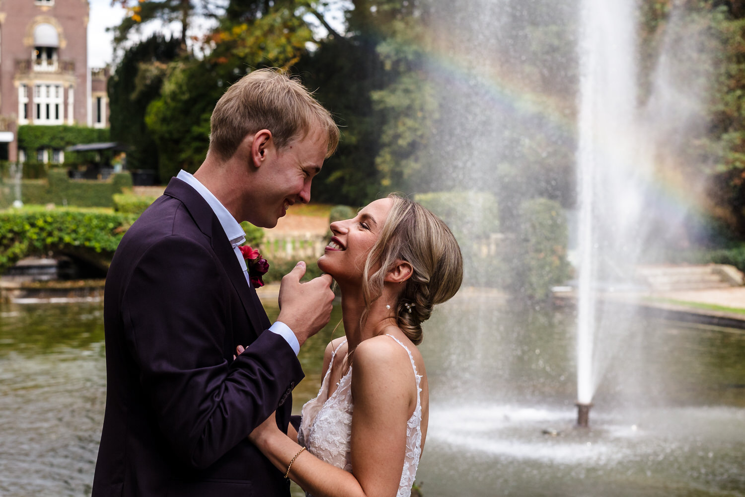 bruidspaar in de kasteeltuin van hooge vuursche met regenboog op de achtergrond