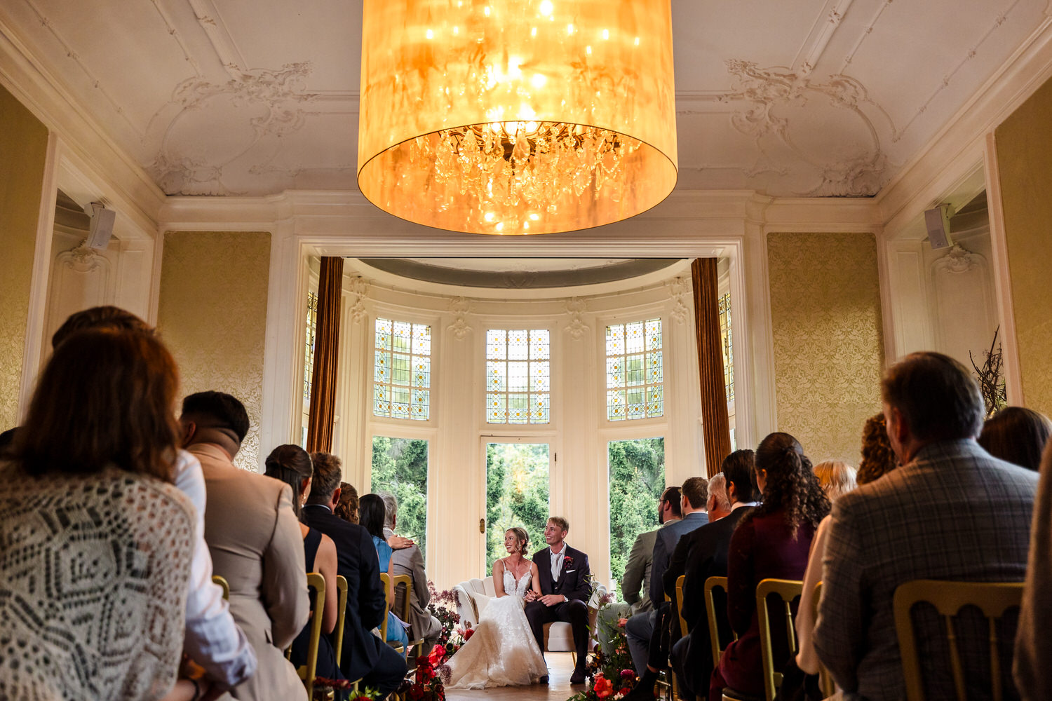 bruidspaar op bankje in ceremoniezaal van kasteel de hooge vuursche