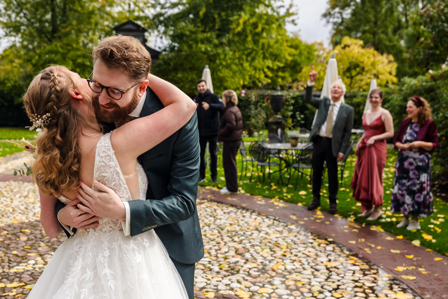first look van bruidspaar met familie op de achtergrond