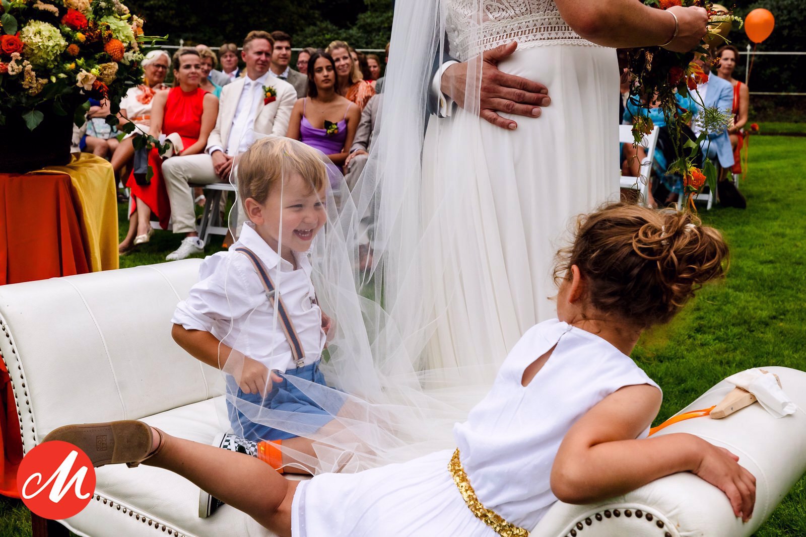 Kindje onder de sluier van de bruid tijdens een ceremonie op Landgoed Groot Warnsborn in Arnhem