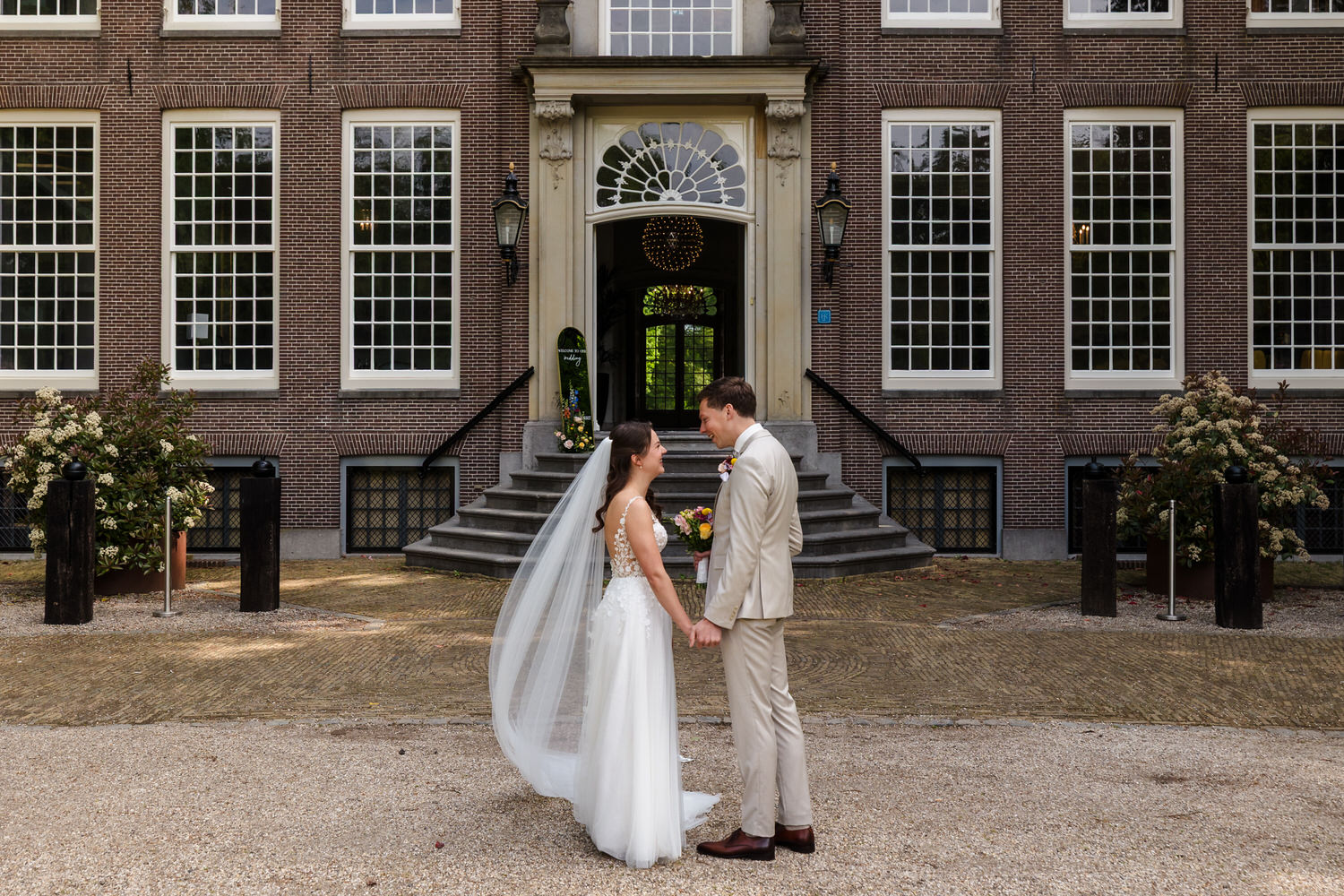 first look van bruidspaar met op de achtergrond het landhuis van buitenplaats sparrendaal