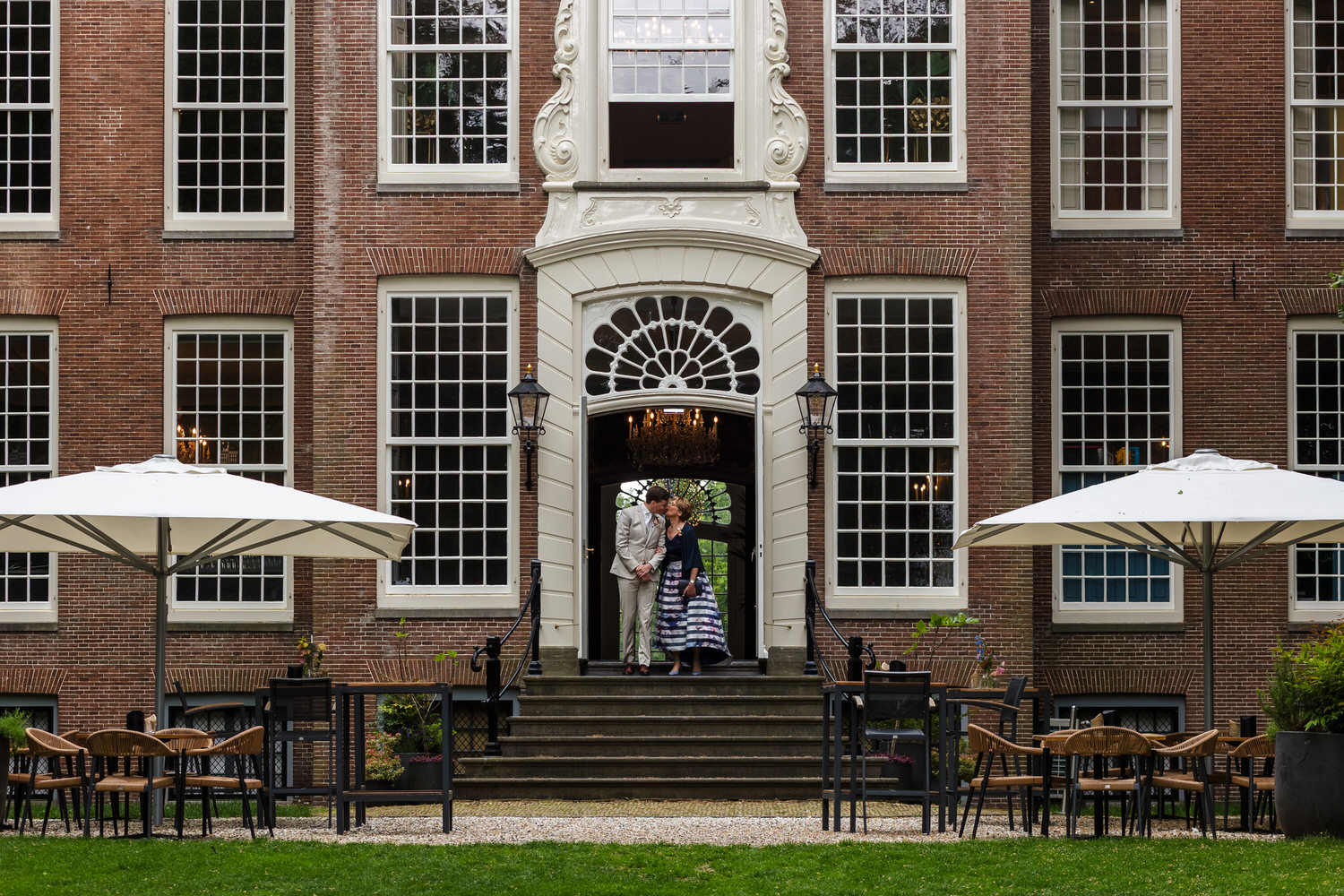 bruidegom komt op samen met zijn moeder voor de ceremonie met op de achtergrond het landhuis van buitenplaats sparrendaal