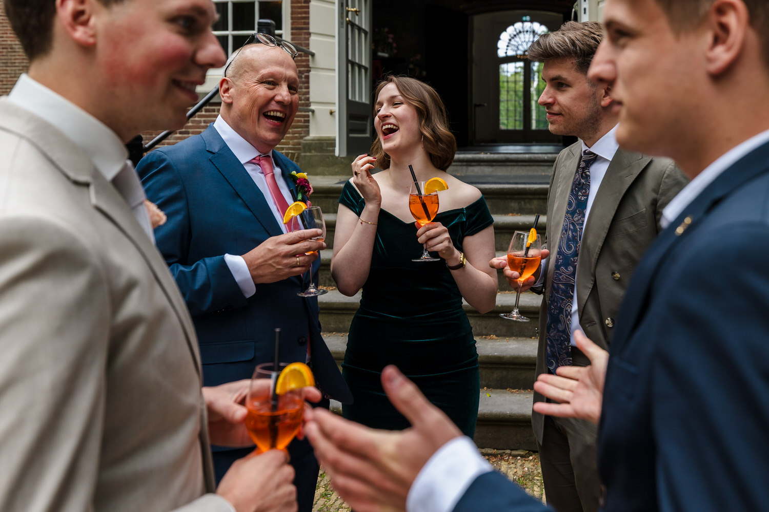lachende bruiloftsgasten met aperol spritz tijdens receptie