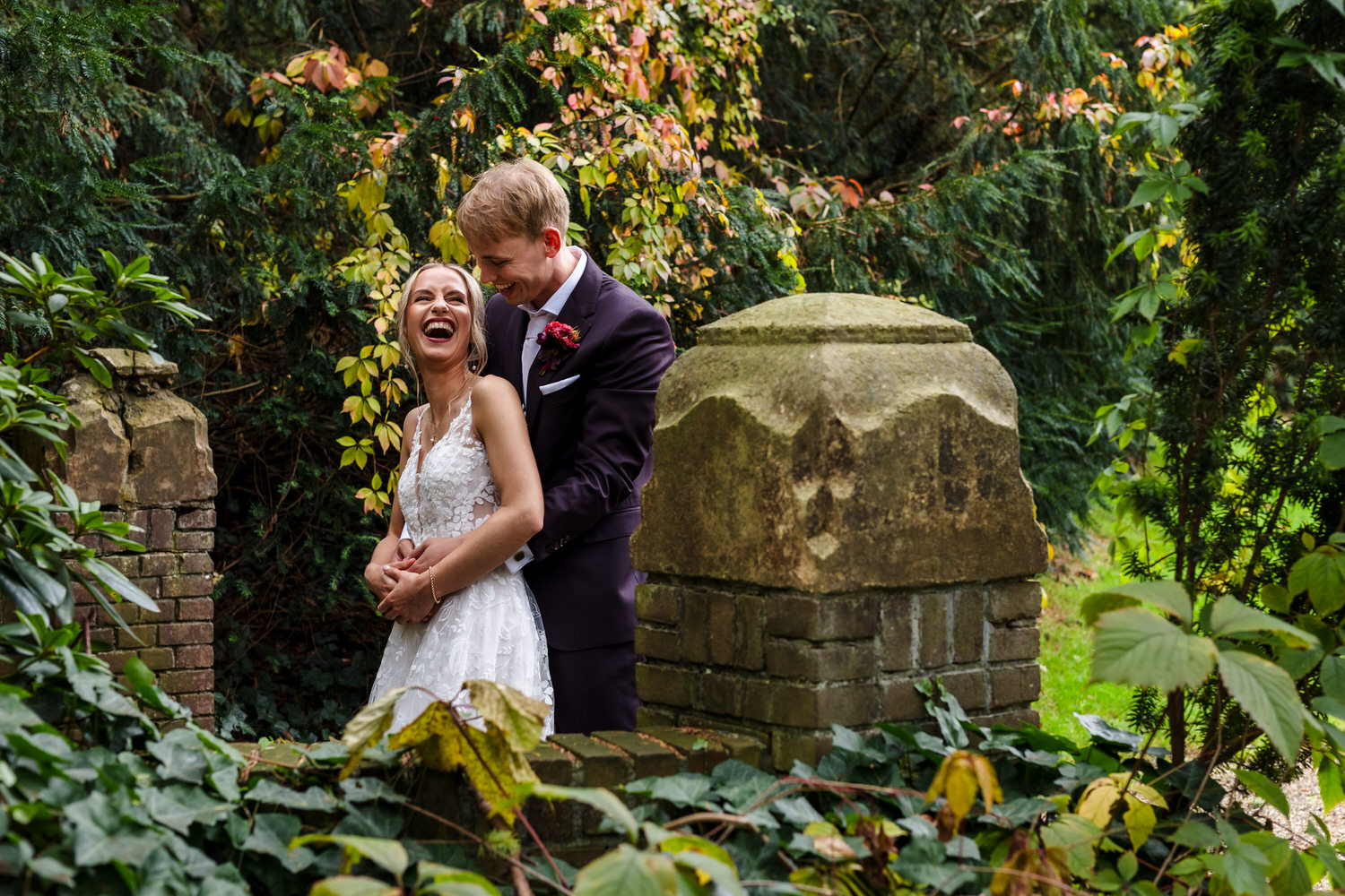lachend bruidspaar tijdens fotoshoot in de kasteeltuin van kasteel de hooge vuursche