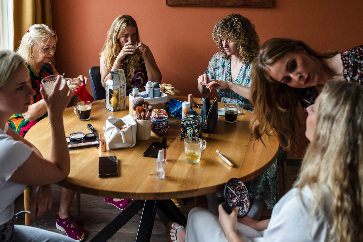 tafel in woonkamer met vrouwen, bruid in de make-up zit rechts vooraan