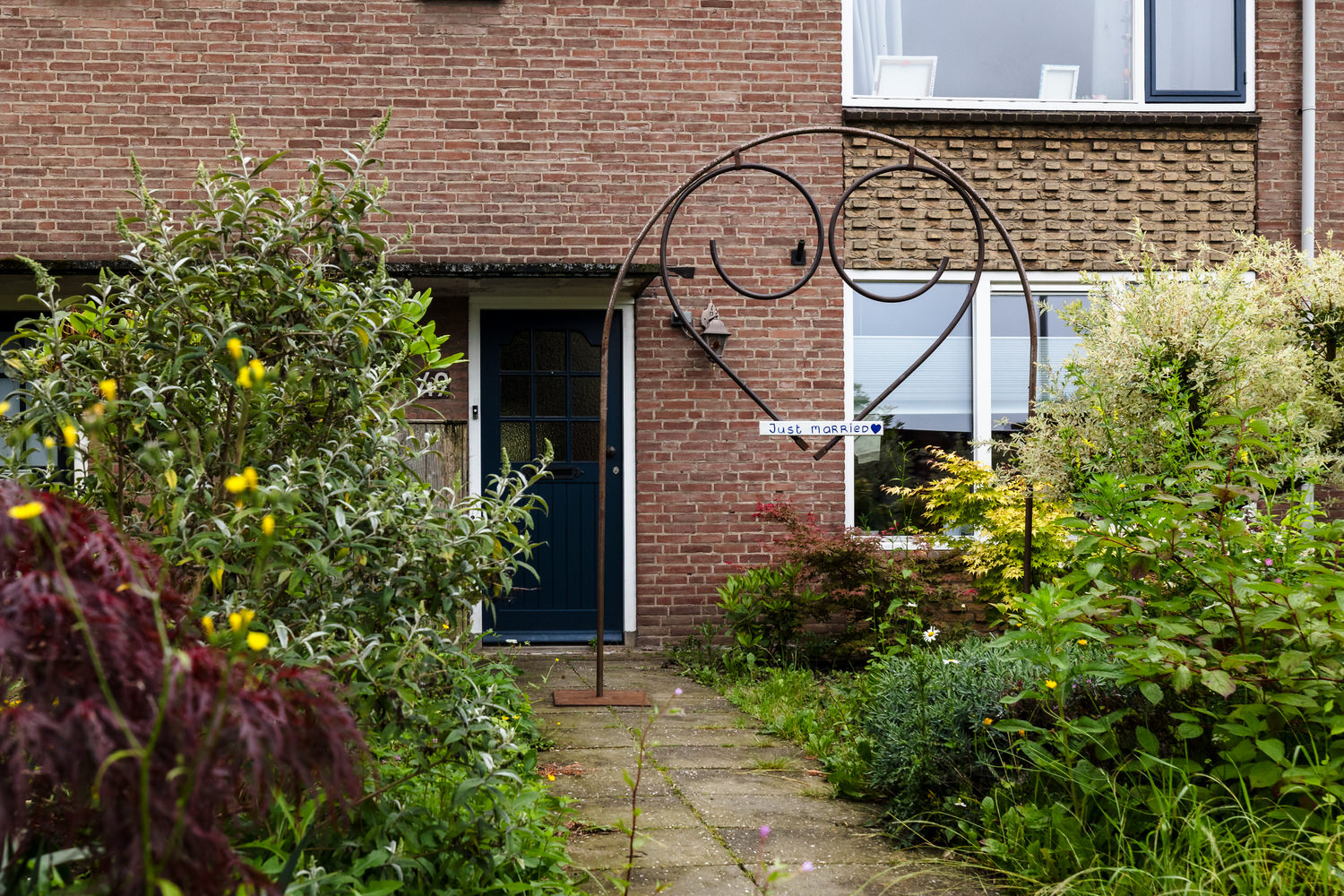huis met in de voortuin een just got married boog