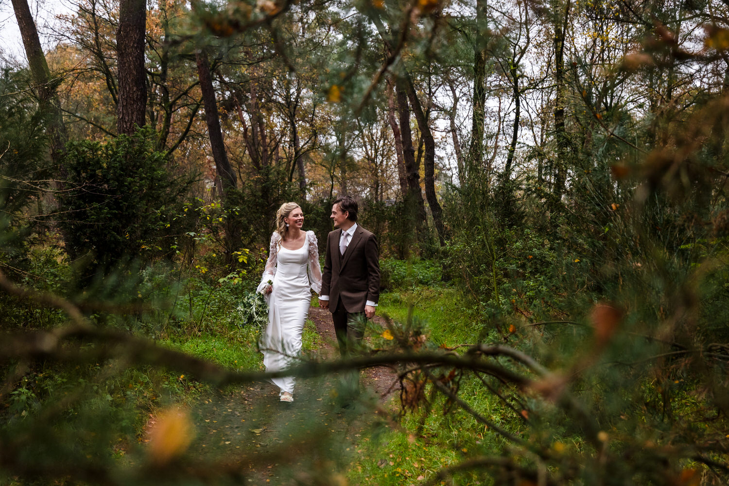 bruidspaar wandelt in het bos tijdens de fotoshoot op hun bruiloft