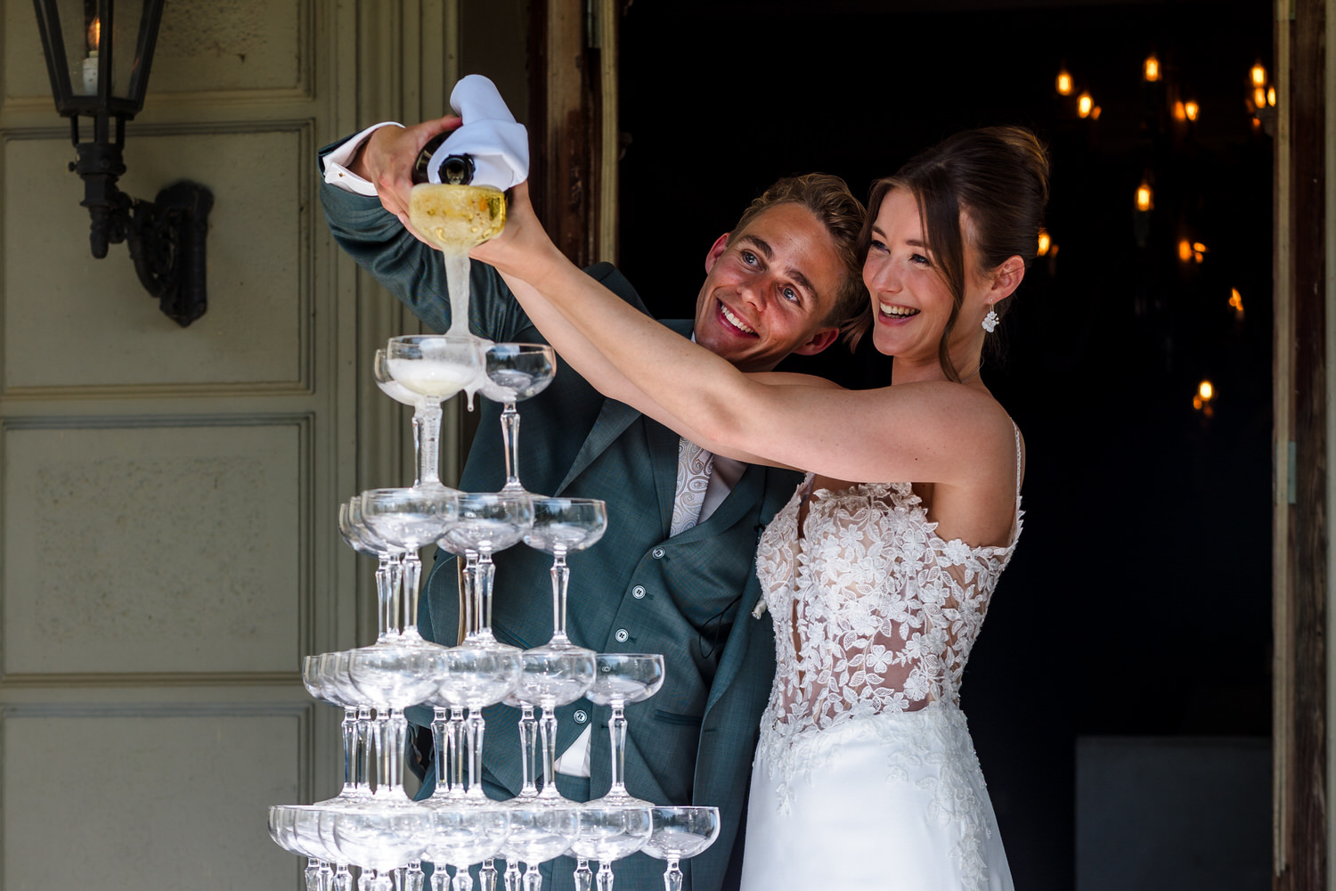 bruidspaar giet champagne in een toren van champagneglazen